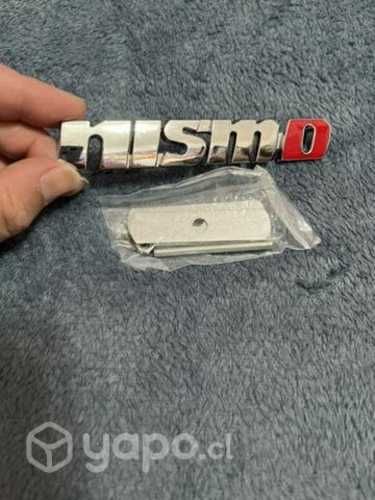 Logo metálico atornillado auto Nissan mismo cromad
